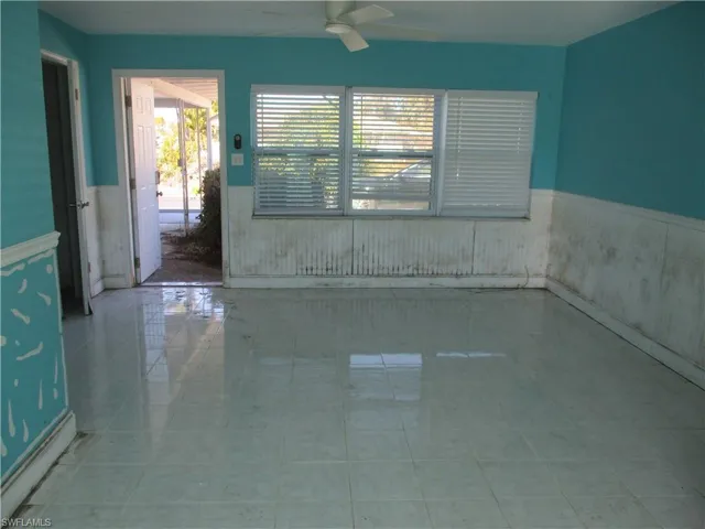 Tiled empty room with wainscoting and ceiling fan