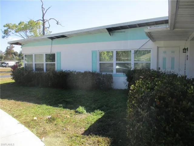 View of side of home with a lawn and stucco siding