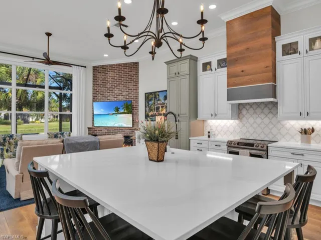 Another view of kitchen showing custom exhaust hood, light wood-type flooring, and brick feature wall