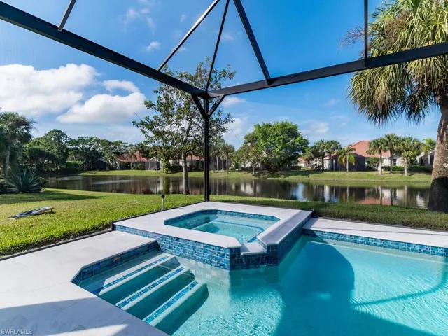 View of pool with a yard, and in-ground hot tub, a water view, and picture-framed screen enclosure