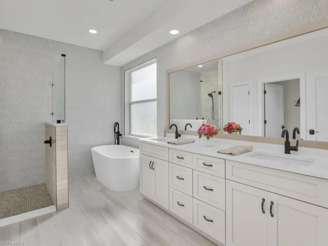 Primary Bathroom featuring double vanity, large shower with freestanding bathtub, custom tile, and vinyl wood-style flooring