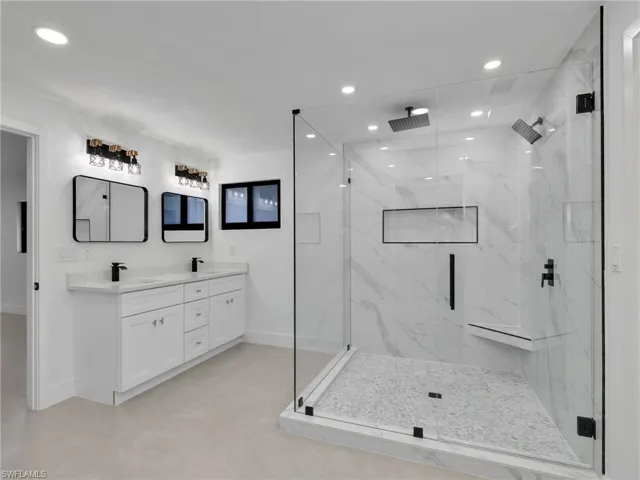 Full bathroom featuring recessed lighting, a marble finish shower, and double vanity