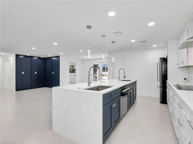 Kitchen featuring white cabinetry, a kitchen island with sink, decorative light fixtures, light stone counters, and recessed lighting
