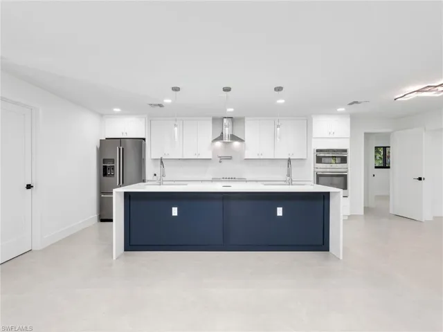 Kitchen with a large island, white cabinetry, stainless steel appliances, hanging light fixtures, and recessed lighting