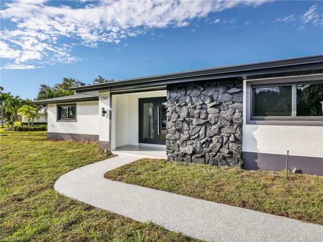 Entrance to property featuring a yard, stone siding, and stucco siding