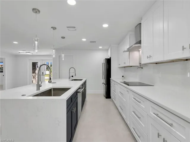 Kitchen featuring white cabinetry, pendant lighting, recessed lighting, light stone counters, and an island with sink