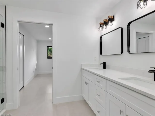 Full bathroom featuring double vanity, recessed lighting, a shower stall, and light tile patterned floors