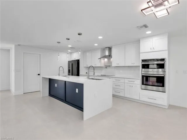 Kitchen featuring decorative light fixtures, white cabinetry, light stone countertops, and recessed lighting