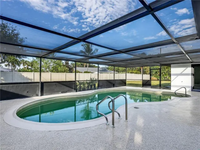 View of swimming pool featuring a sunroom, glass enclosure, and a fenced backyard