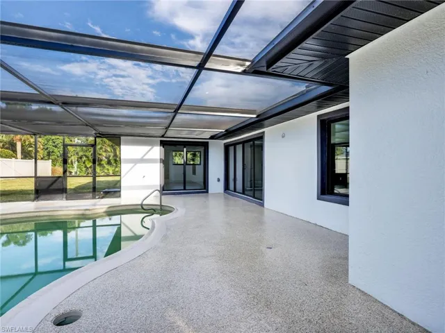 Outdoor pool featuring a sunroom, a patio, and glass enclosure