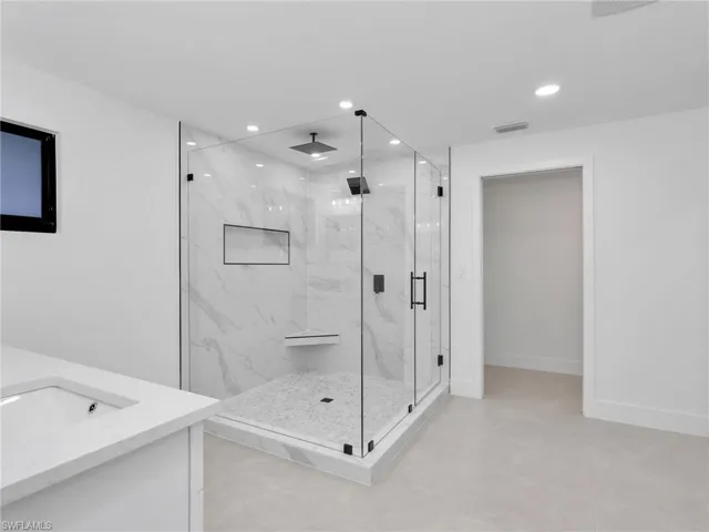 Full bath with vanity, a marble finish shower, recessed lighting, and light tile patterned flooring