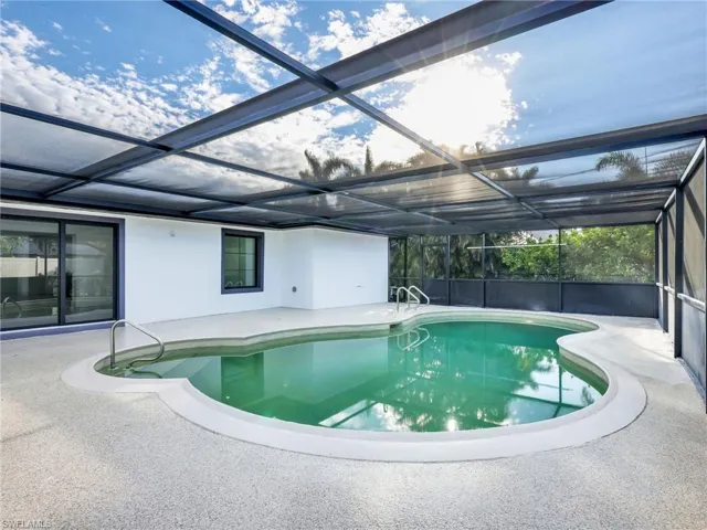 Swimming pool featuring a sunroom, glass enclosure, and a patio area