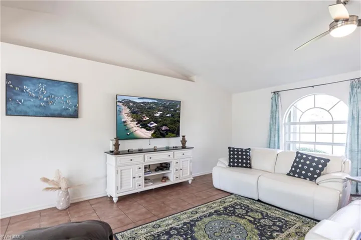 Tiled living room with lofted ceiling and a ceiling fan