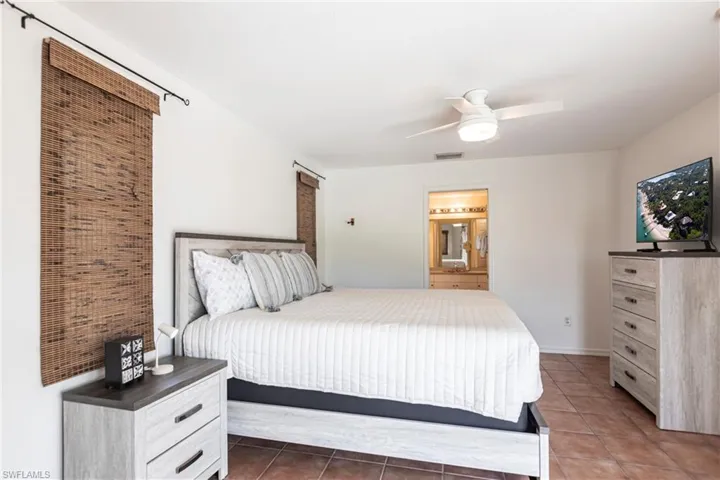 Bedroom featuring tile patterned floors, ensuite bath, and a ceiling fan