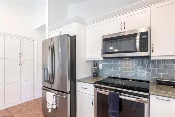 Kitchen featuring appliances with stainless steel finishes, backsplash, and white cabinetry