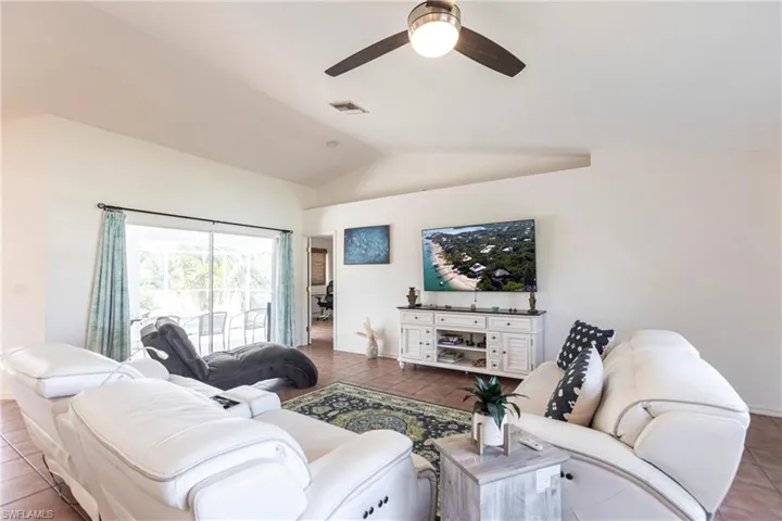 Tiled living area featuring a ceiling fan and vaulted ceiling