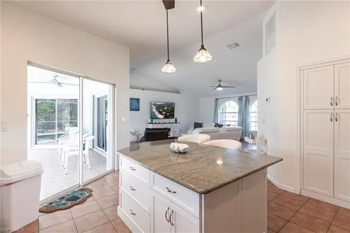 Kitchen featuring ceiling fan, lofted ceiling, light tile patterned floors, a kitchen island, and pendant lighting