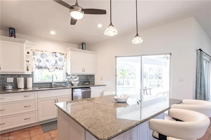 Kitchen featuring dishwasher, ceiling fan, tasteful backsplash, white cabinets, and dark stone countertops