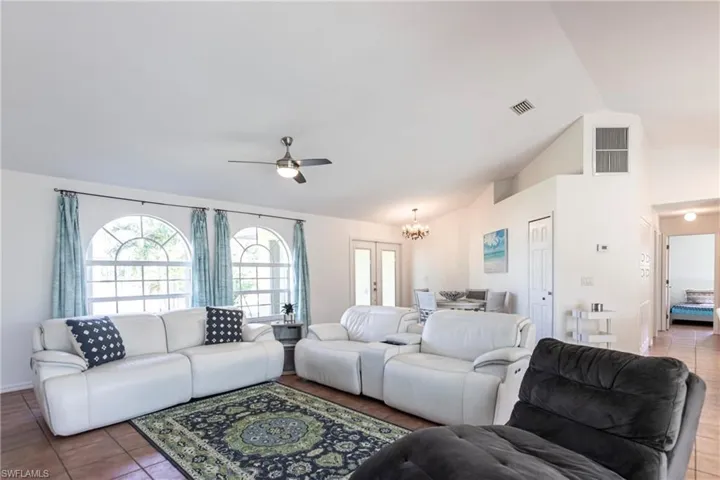 Living area with a chandelier, plenty of natural light, lofted ceiling, a ceiling fan, and tile patterned flooring