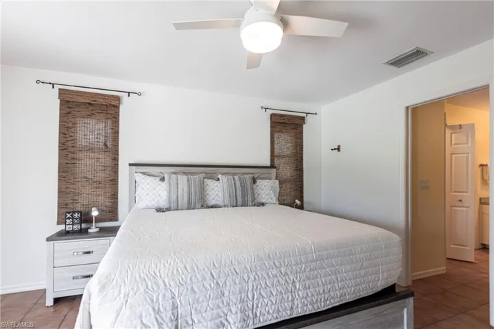 Tiled bedroom featuring ceiling fan and baseboards