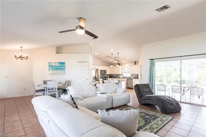 Living room with light tile patterned floors, a chandelier, a ceiling fan, recessed lighting, and high vaulted ceiling