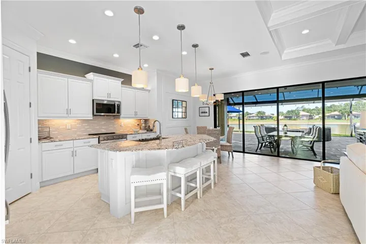 WHITE BUILDER’S UPGRADE STAGGERED CABINETS WITH UPGRADED CABINET MOLDINGS PLUS SOFT-CLOSE DRAWERS & CONVENIENT SLIDE-OUT DRAWERS! NOTE THE 7 FOOT BRONZE STACKABLE SLIDER DOORS (4) LEADING OUT TO THE COVERED LANAI.