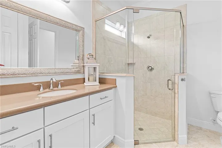 ANOTHER FULL BATHROOM WITH A WALK-IN GLASS SHOWER & CUSTOM MIRROR SURROUND.