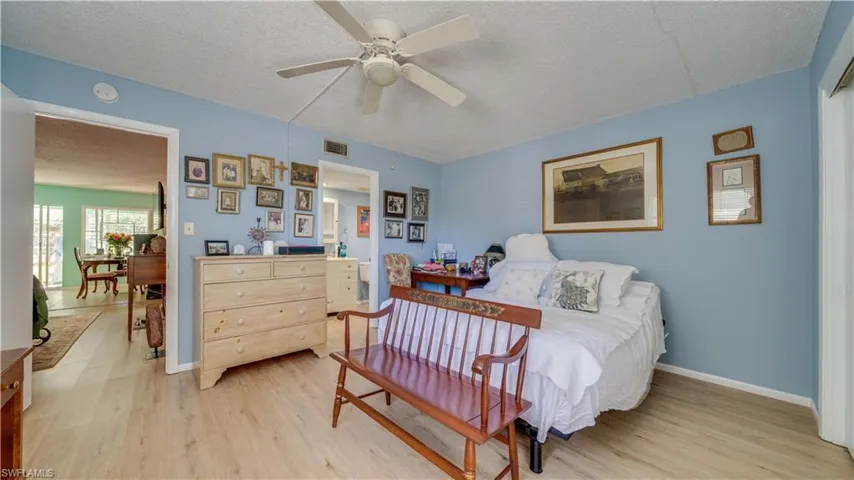 Bedroom with visible vents, baseboards, a textured ceiling, and light wood finished floors