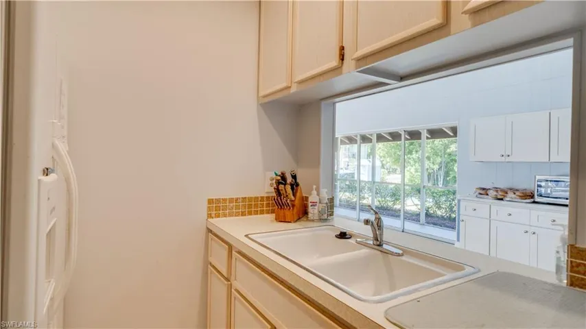 Kitchen with stainless steel microwave, light countertops, decorative backsplash, and a sink