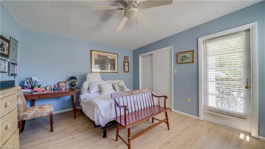 Bedroom with light wood-style flooring, baseboards, and a textured ceiling