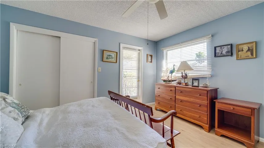 Bedroom with a closet, ceiling fan, a textured ceiling, and light wood-style floors