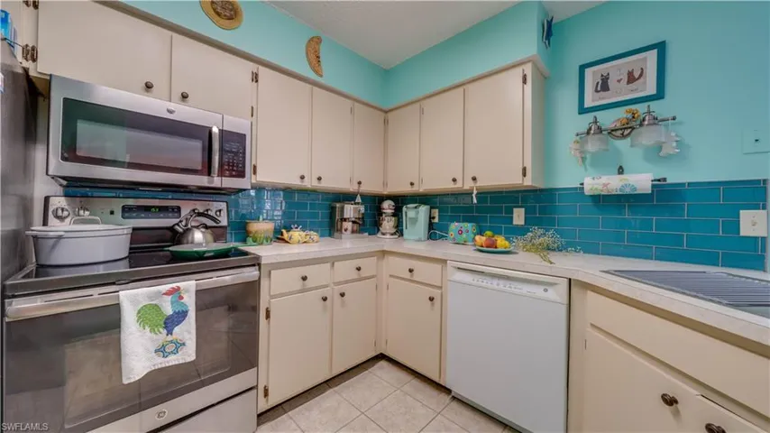 Kitchen with light tile patterned floors, decorative backsplash, stainless steel appliances, and light countertops
