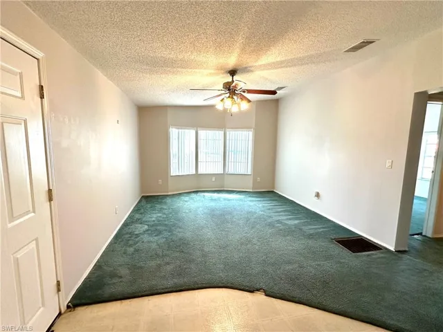 Unfurnished room featuring carpet, a textured ceiling, and ceiling fan
