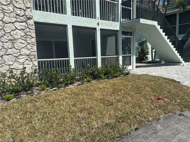 Current View of home's exterior featuring a yard, stone siding, a sunroom, and stucco siding