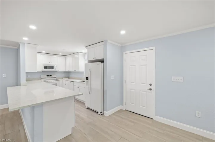 Kitchen with NEW white appliances, Quartz counters, white wood cabinetry, crown molding, and light wood-style ceramic floors