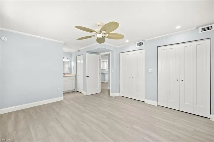 Guest bedroom with crown molding, multiple closets, baseboards, light wood-type ceramic plank flooring, and recessed lighting