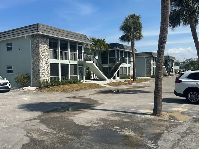Current View of apartment building / complex featuring stairs and uncovered parking