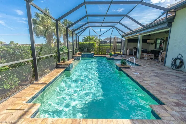 View of swimming pool featuring glass enclosure and a patio