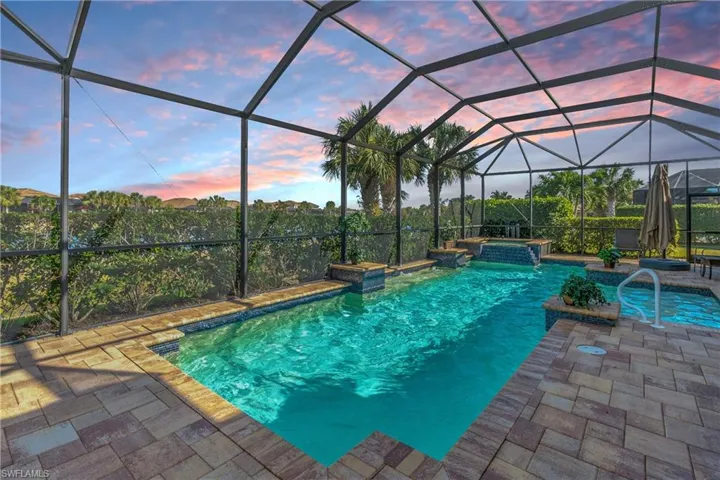 Pool at dusk featuring a lanai and a patio