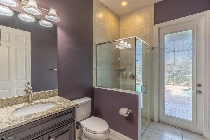 Bathroom with vanity, tile patterned floors, a wealth of natural light, and a shower with shower door