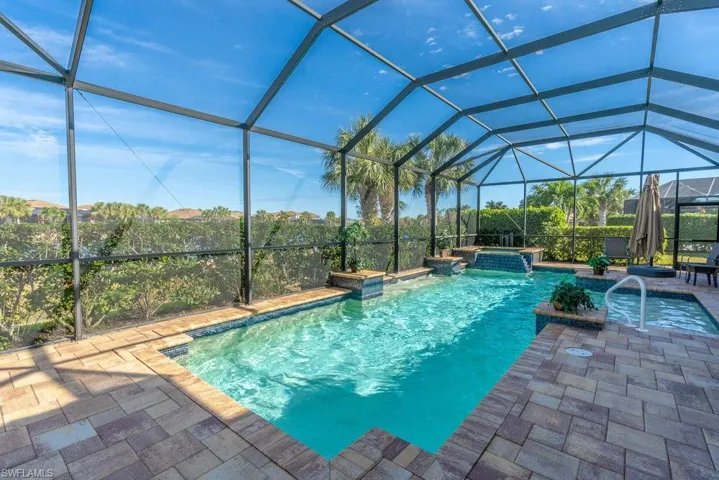 View of pool with glass enclosure and a patio area