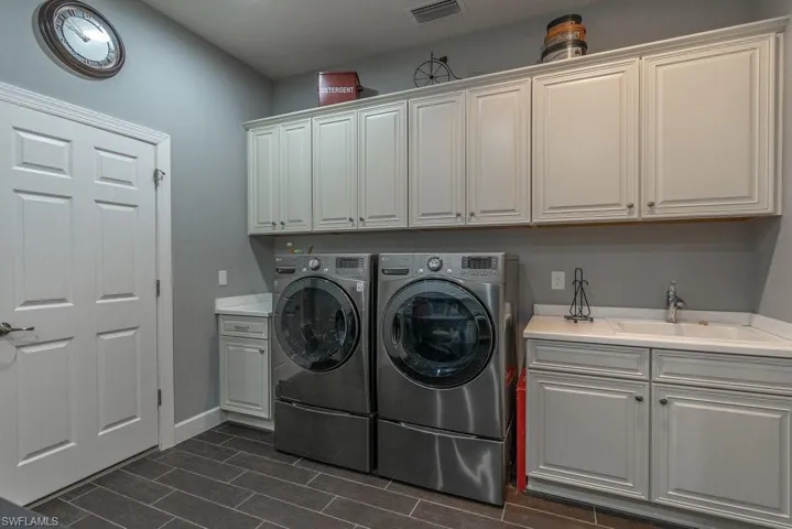 Washroom with cabinets, sink, washing machine and dryer, and dark wood-type flooring