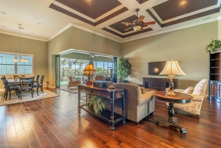 Living room featuring dark hardwood / wood-style flooring, crown molding, a wealth of natural light, and coffered ceiling