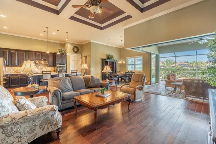 Living room with crown molding, dark wood-type flooring, and coffered ceiling