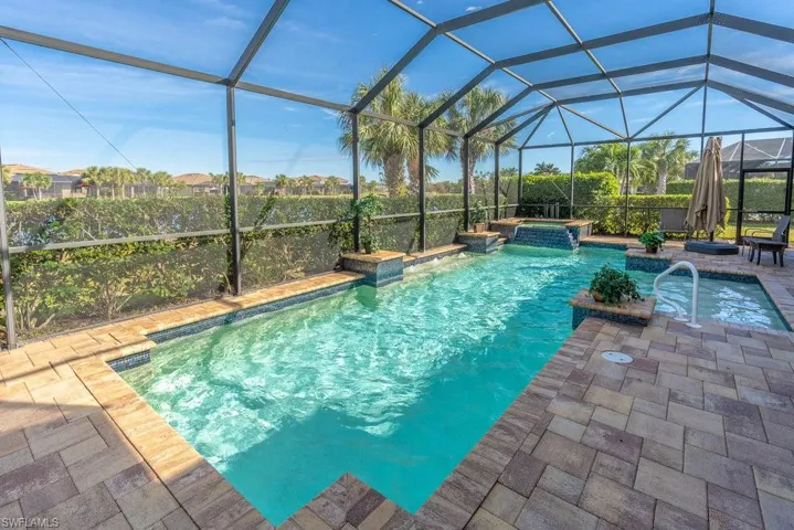 View of swimming pool featuring glass enclosure, an in ground hot tub, and a patio