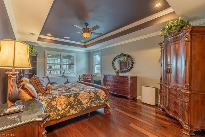 Bedroom featuring a tray ceiling, ceiling fan, dark hardwood / wood-style flooring, and ornamental molding
