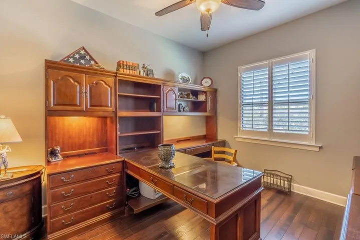 Home office with ceiling fan and dark wood-type flooring