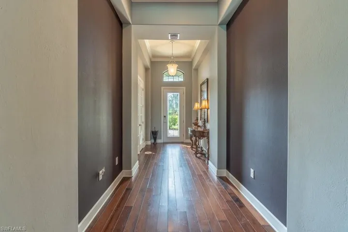 Doorway with dark hardwood / wood-style floors and ornamental molding