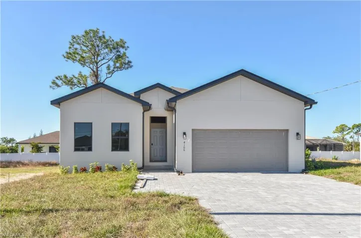 View of front of home featuring a garage, decorative driveway, and stucco siding