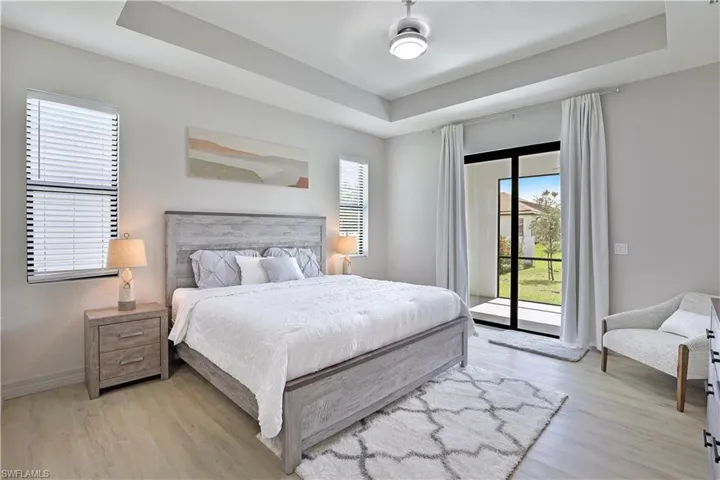 Bedroom featuring a tray ceiling, access to exterior, and light wood-type flooring